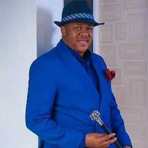 Portrait of Nigerian actor Francis Duru wearing a dark suit, smiling at a film event in Lagos.