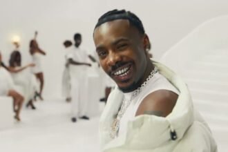 Young Jonn dancing on a white set surrounded by partygoers in the Glass in the Air official music video.