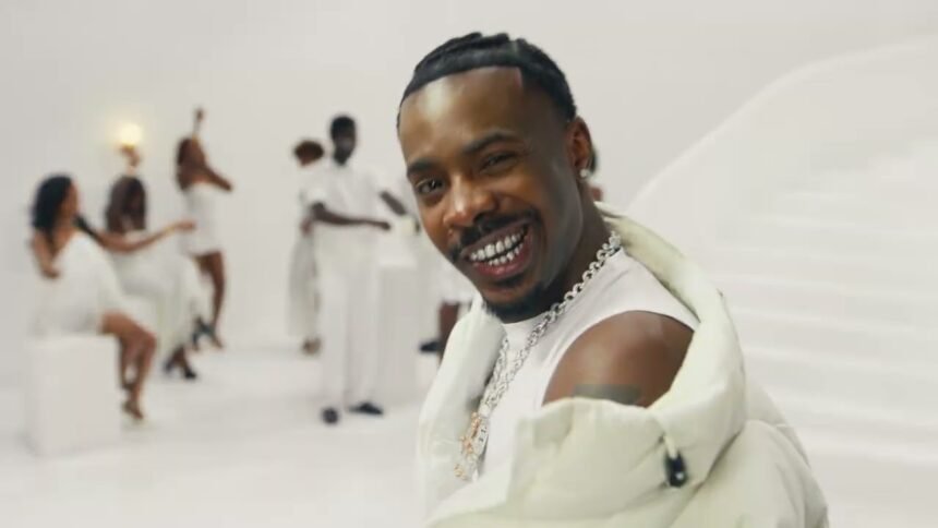 Young Jonn dancing on a white set surrounded by partygoers in the Glass in the Air official music video.