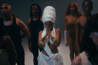 Zee Nxumalo, Dlala Thukzin, Funky QLA and TBO performing together on a stage set with bright lights in the Guqa (My Prayer) music video.