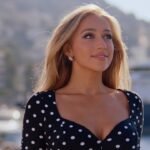 Tate McRae sings and dances in a bright studio set for the Housewife music video, wearing a sleek outfit with dynamic lighting.