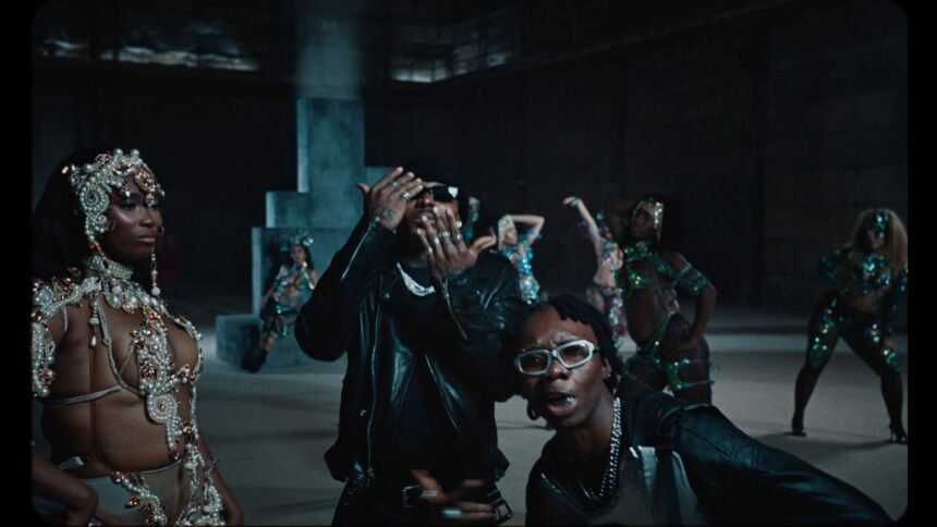 Blaqbonez and Asake performing together on a bright set with dancers in carnival outfits for the Ikebe 3000 music video
