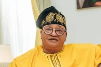Jide Kosoko standing in front of a movie poster, looking thoughtful about the financial loss of his recent film