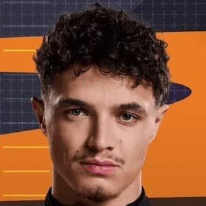 Lando Norris wearing a McLaren racing suit, standing beside his Formula One car at a race track
