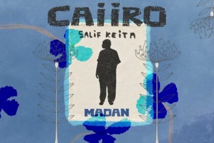 Salif Keita singing on stage, with the cover art for the Caiiro Remix of 'Madan' displayed.