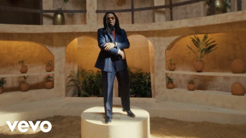 Olamide in the official Burukutu video, wearing a bright outfit and standing against a city backdrop.