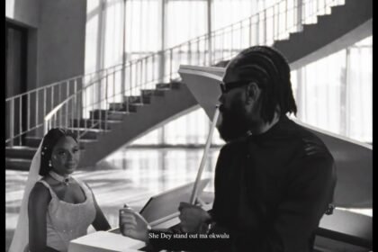 Phyno standing in a softly lit studio, wearing a casual shirt, singing into a microphone while a camera crew records the "Beautiful" music video.