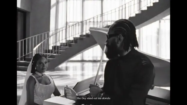 Phyno standing in a softly lit studio, wearing a casual shirt, singing into a microphone while a camera crew records the "Beautiful" music video.