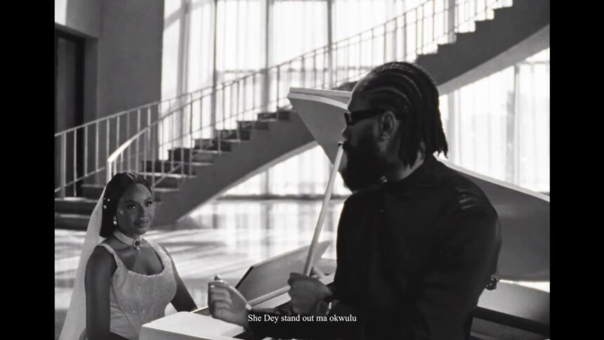 Phyno standing in a softly lit studio, wearing a casual shirt, singing into a microphone while a camera crew records the "Beautiful" music video.