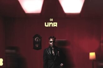 Ibraah singing in the official audio video for his song Una, showing him in front of a dark background with subtle lighting.