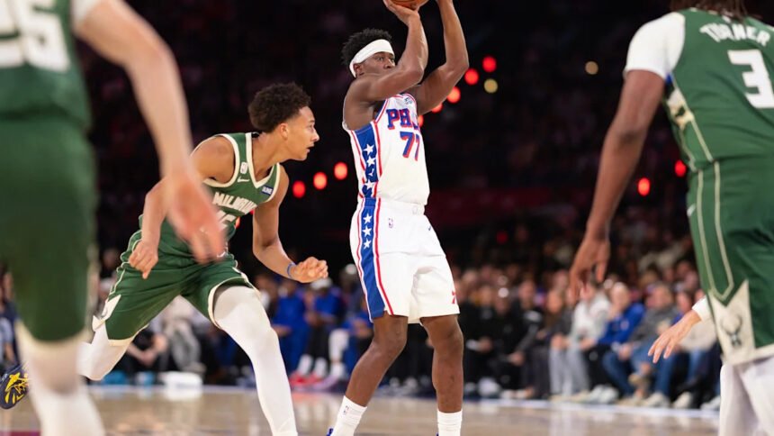VJ Edgecombe in a Philadelphia 76ers jersey standing on the basketball court during a game, looking focused.